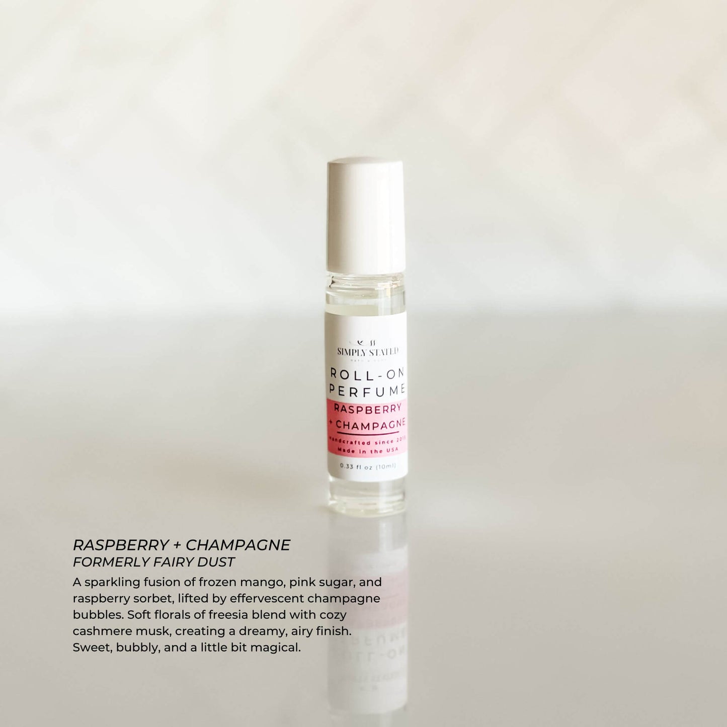 Raspberry + Champagne Roll-On Perfume bottle with scent description text overlay on marble background