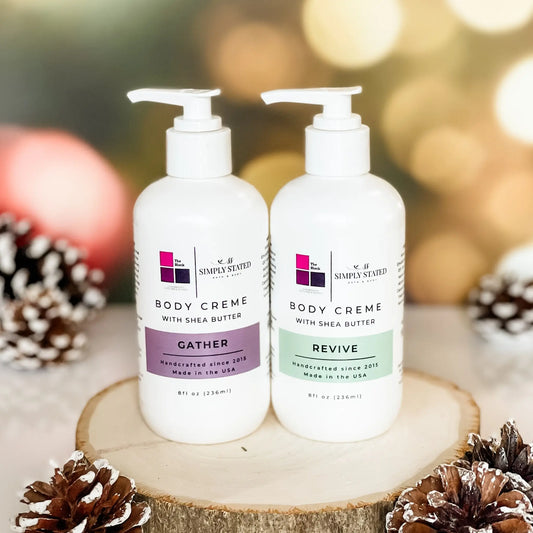 The Block x Simply Stated duo Body Creme in large 8 oz with pump featuring scents in Gather and Revive with winter glow and pinecone decorations.