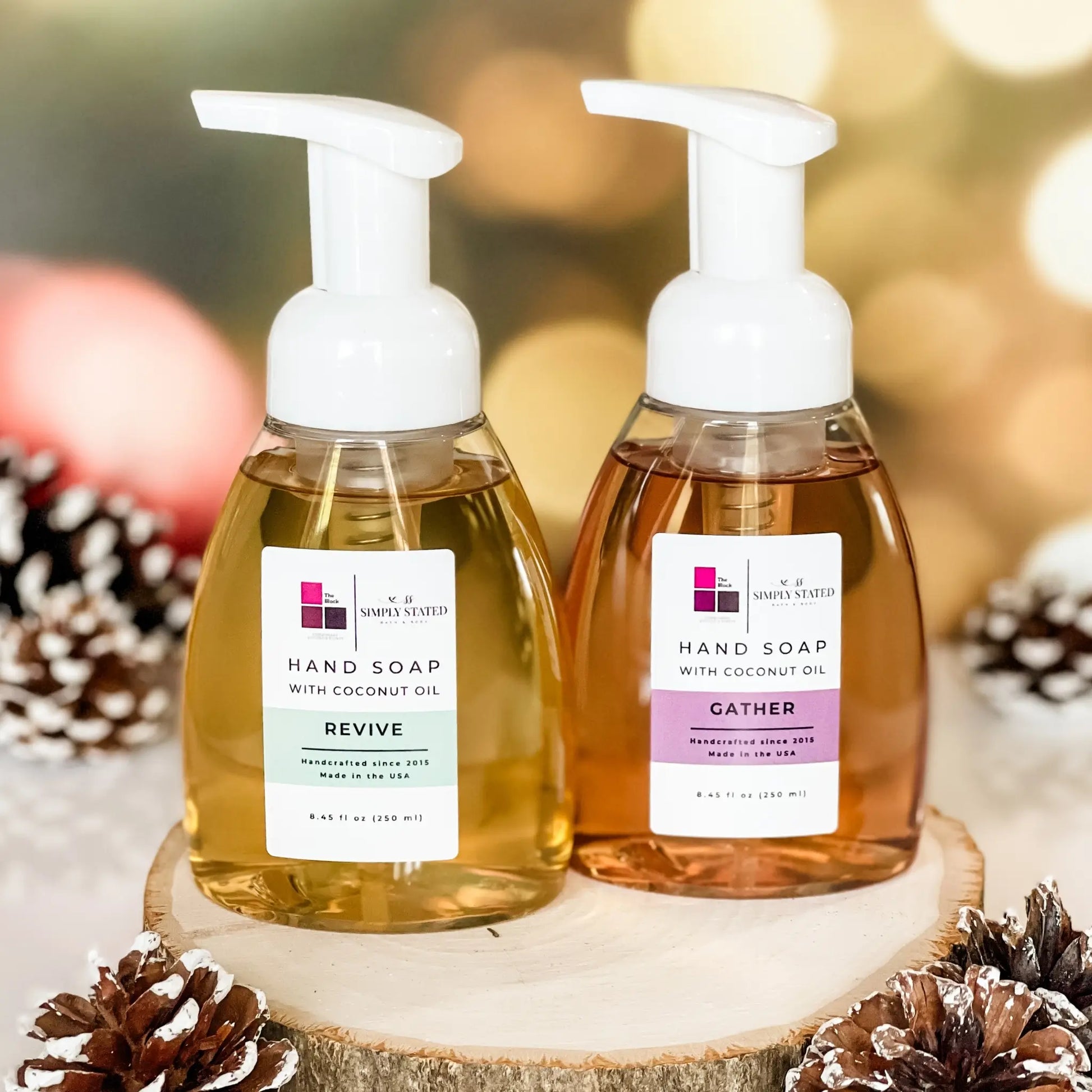 The Block x Simply Stated Foaming Hand Soap featuring scents Revive and Gather with a warm winter glow background and subtle pinecone decorations.