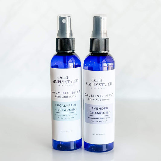 Simply Stated Bath & Body Calming Mist duo featuring Eucalyptus + Spearmint and Lavender + Chamomile. Body and room sprays crafted with essential oils to refresh, relax, and soothe. Presented in sleek 4oz blue bullet bottles.