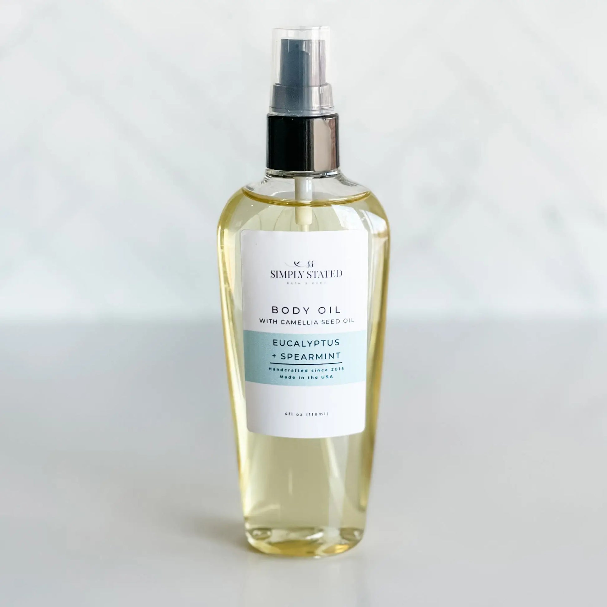 Body oil spray bottle with a label on a white background