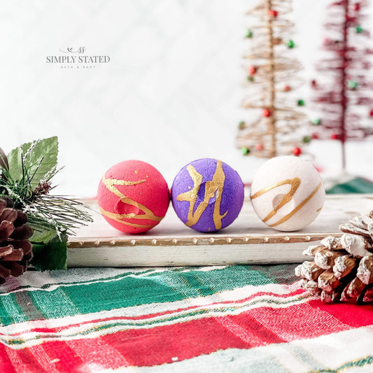 Limited edition bath bombs from the Christmas Collection. Christmas Cranberry (red), Holiday Pomegrante (purple), and Amaretto Cheer (natural)