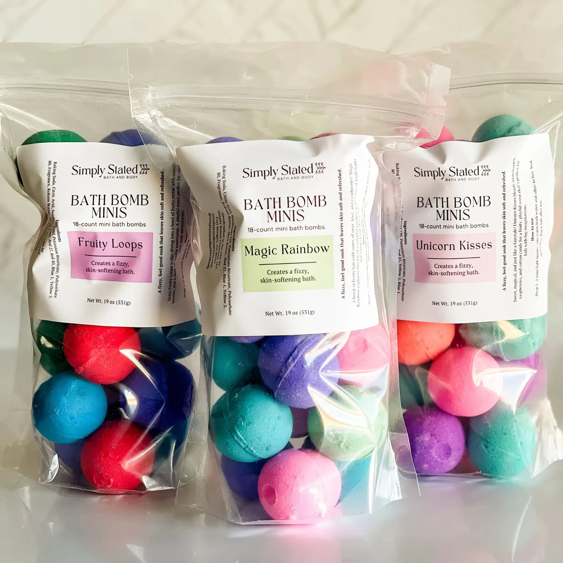 Three bags of bath bomb minis with colorful bath bombs on a white background