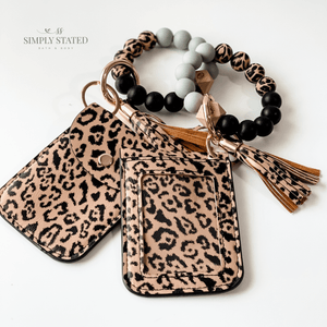 Card case in leopard print. Includes silicone beaded bracelet keychain (solid black, grey, and leopard print) and matching leopard print tassle
