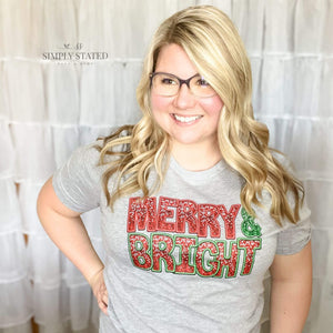 Graphic Tee in Heather Grey with font in a faux embroidery, faux sequin style saying "Merry & Bright"