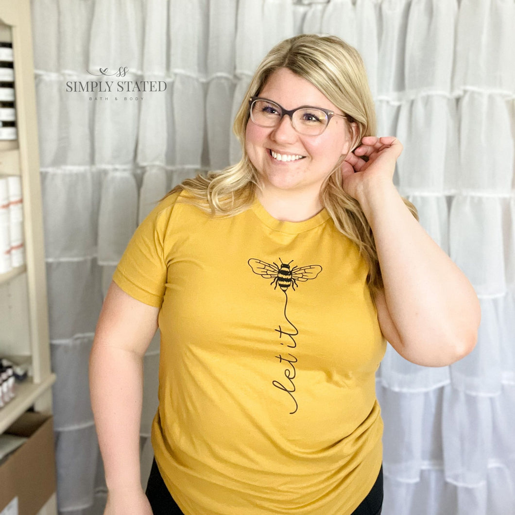 Graphic tee in mustard yellow with design of Let it Bee
