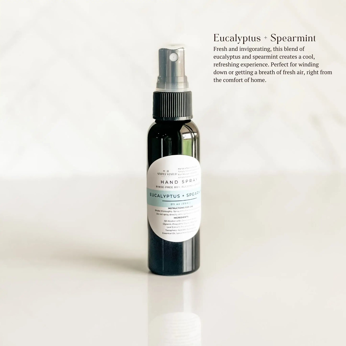 Hand spray bottle labeled 'Eucalyptus + Spearmint' on a light background