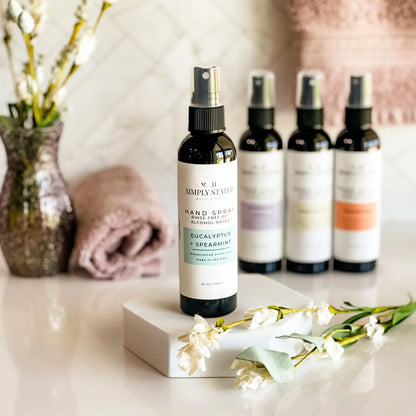 Hand sanitizer bottles with labels on a surface with flowers and towels in the background