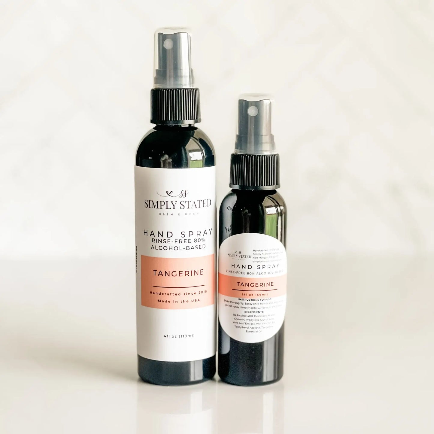 Two bottles of Simply Stated Tangerine hand spray on a light background