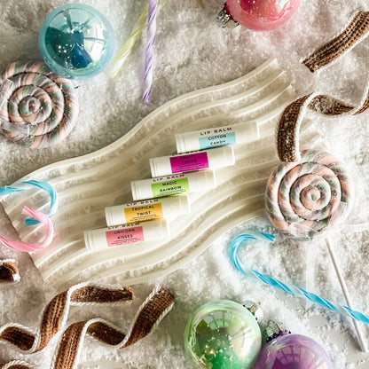 Set of lip balms on a decorative tray with candy-themed items.
