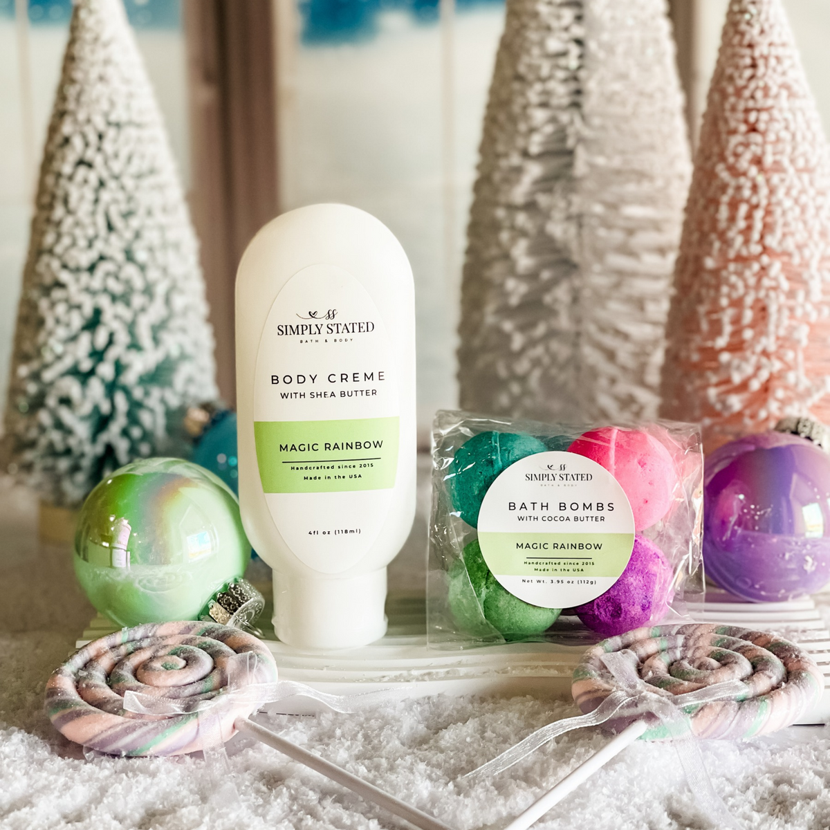 Simply Stated magic rainbow shea butter body creme and cocoa butter bath bombs with pastel trees and ornaments