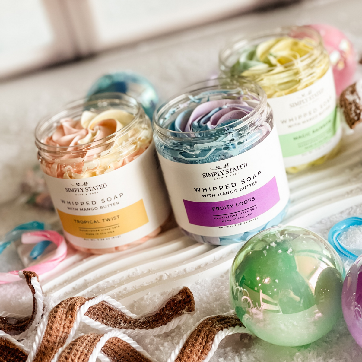 Simply Stated tropical twist, fruity loops and magic rainbow whipped soap jars open to show colorful swirled tops