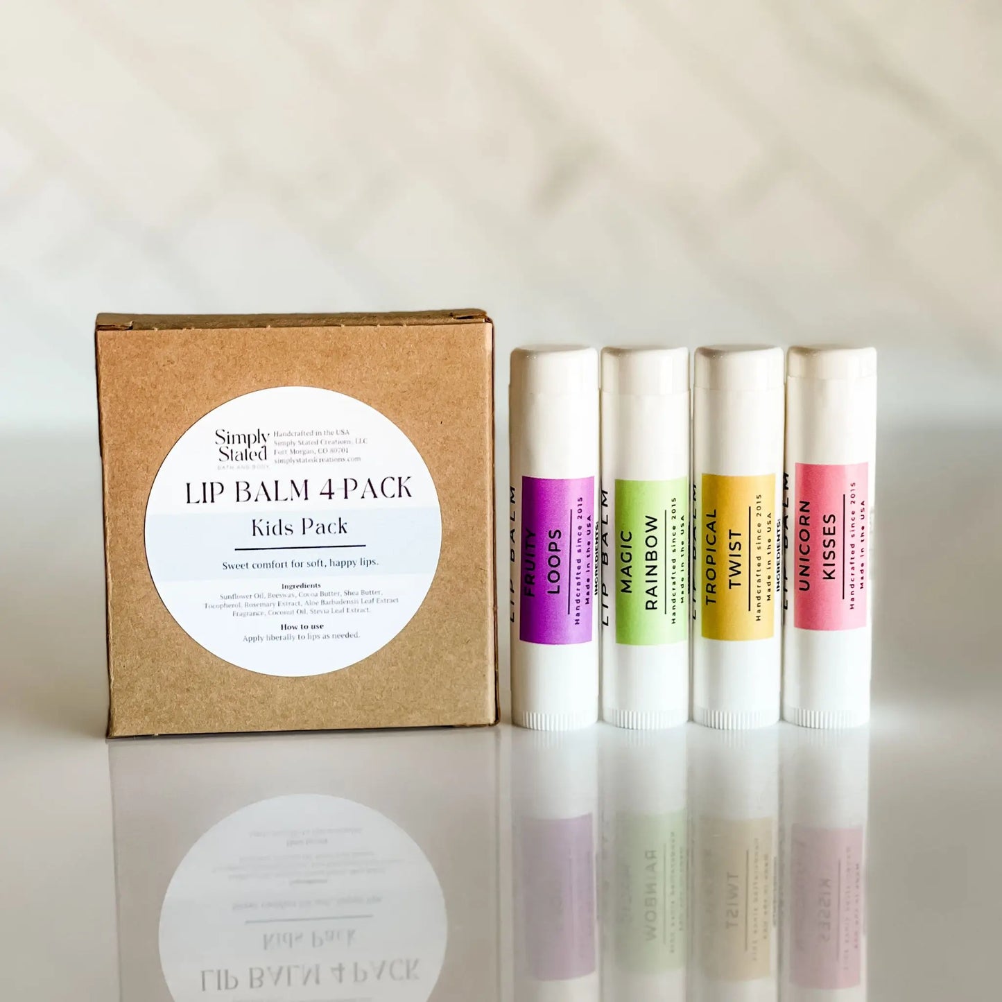 Lip balm 4-pack with a cardboard box on a reflective surface labeled 'Kids Pack.'