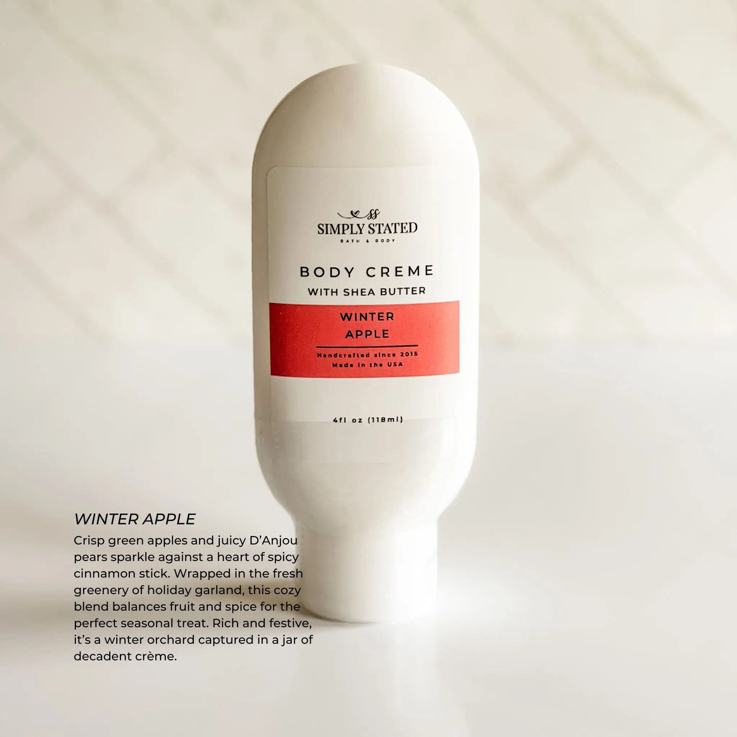 Body crème bottle labeled 'Simply Stated' with 'Winter Apple' flavor on a light background