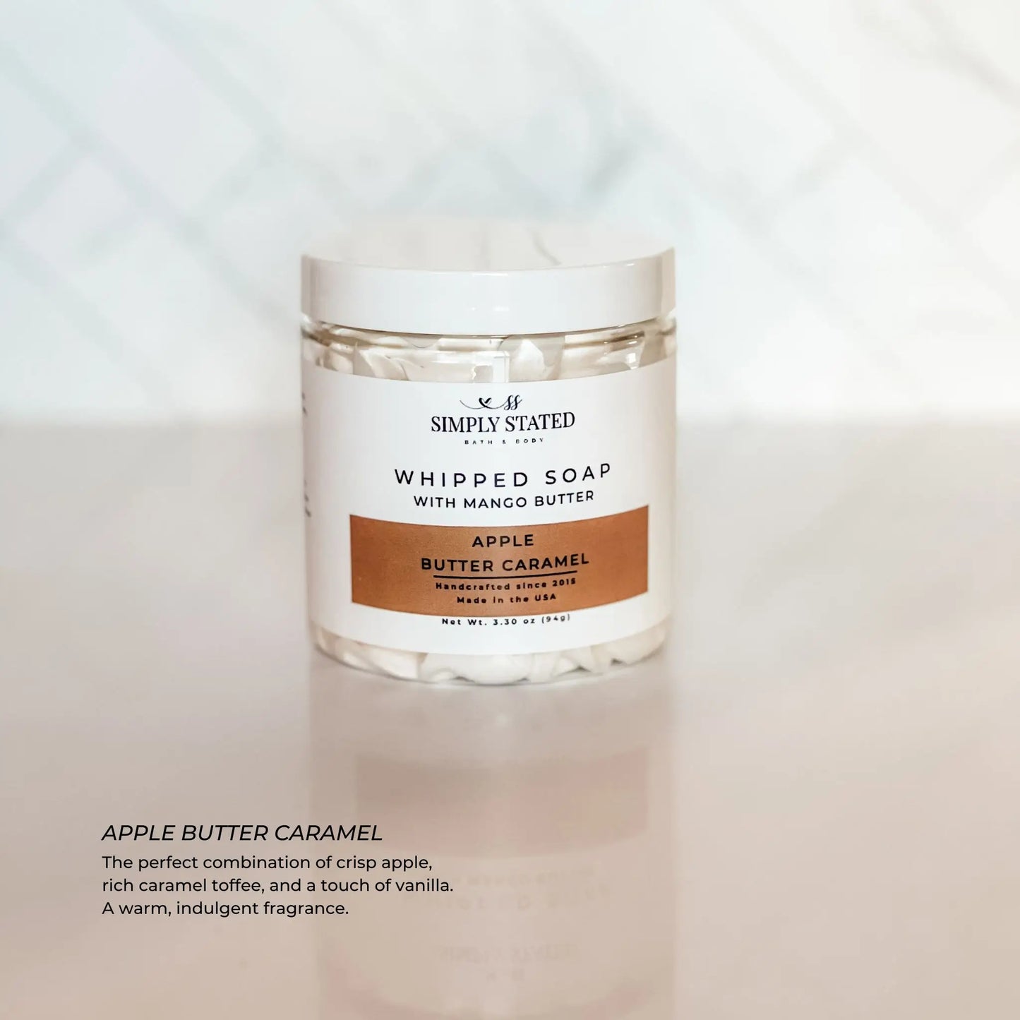 Jar of whipped soap labeled 'Simply Stated' with 'Apple Butter Caramel' on a light background