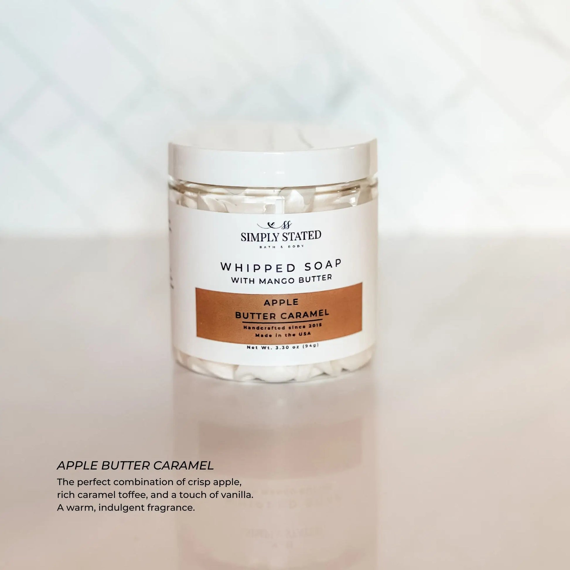 Jar of whipped soap labeled 'Simply Stated' with 'Apple Butter Caramel' on a light background