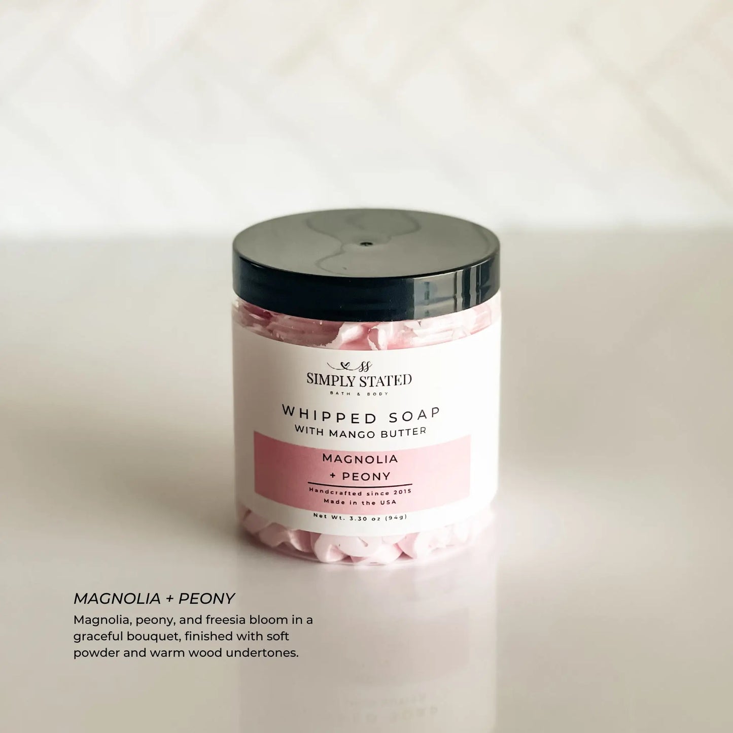 Jar of whipped soap with a black lid on a white background