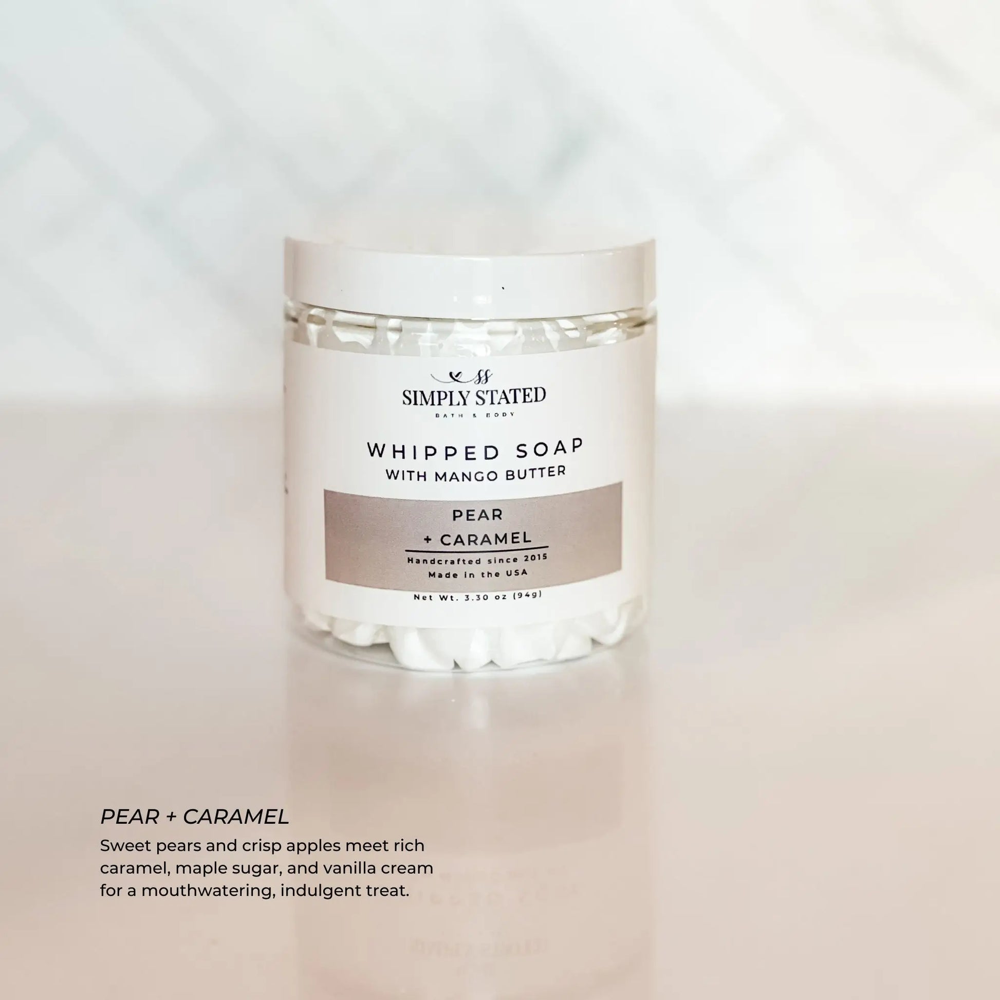 Jar of whipped soap labeled 'Pear + Caramel' by Simply Stated on a light background
