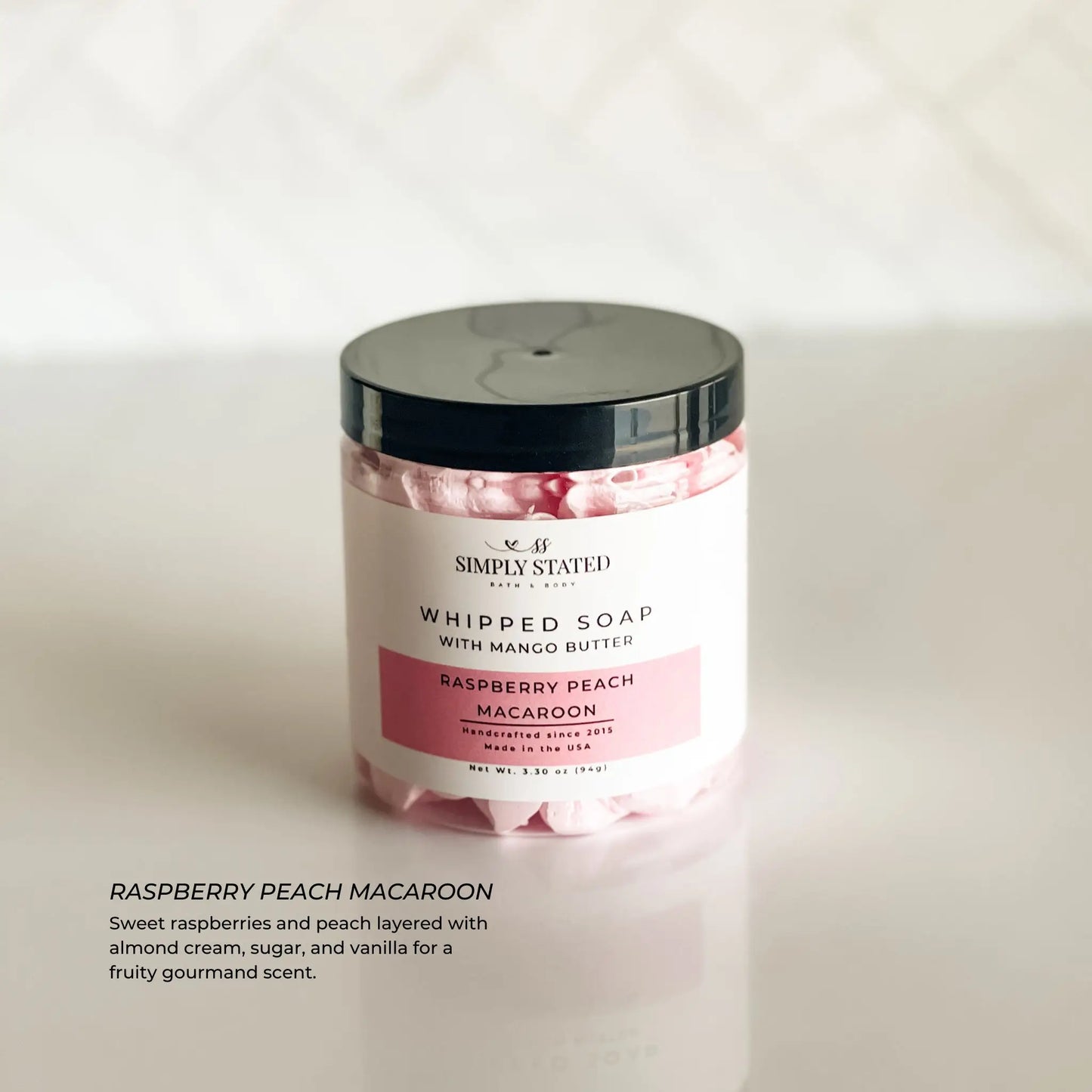 Whipped soap container with raspberry peach macaron flavor on a white background