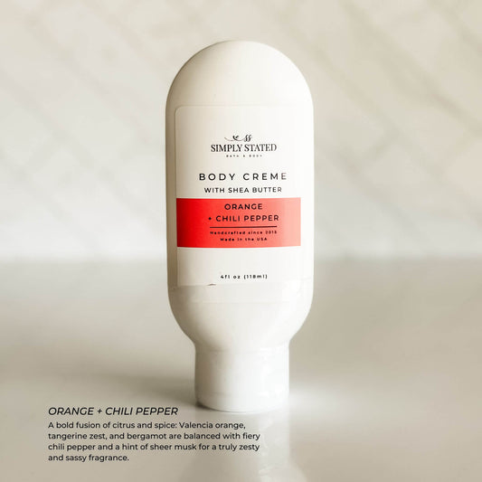 Simply Stated Body Crème in Orange Chili Pepper scent with bold, citrus spice notes. Shown with bright orange label and clean white background for seasonal product feature.