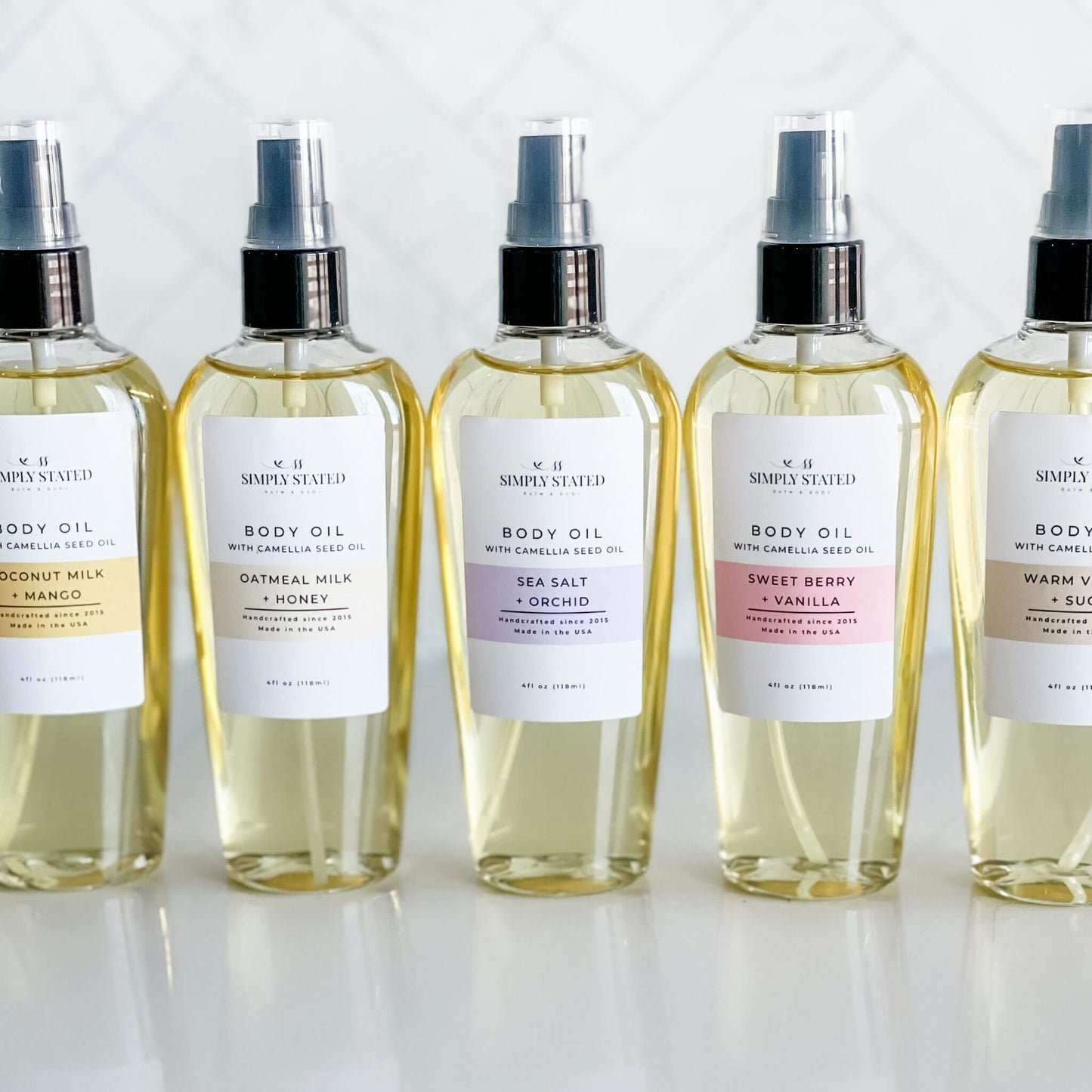 Simply Stated Bath & Body's complete Signature Body Oil collection in 4oz bottles, showcasing the Coconut Milk + Mango, Oatmeal Milk + Honey, Sea Salt + Orchid, Sweet Berry + Vanilla, and Warm Vanilla + Sugar fragrances for luxurious hydration.