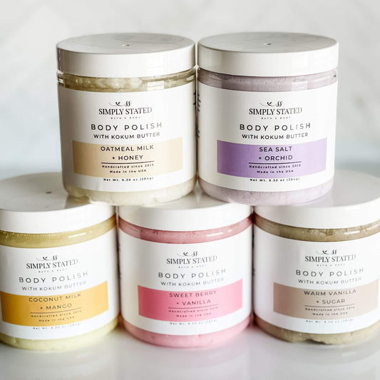 Simply Stated Signature Line Body Polish collection, featuring five scents: Coconut Milk + Mango, Oatmeal Milk + Honey, Sea Salt + Orchid, Sweet Berry + Vanilla, and Warm Vanilla + Sugar in 9.3 oz jars.