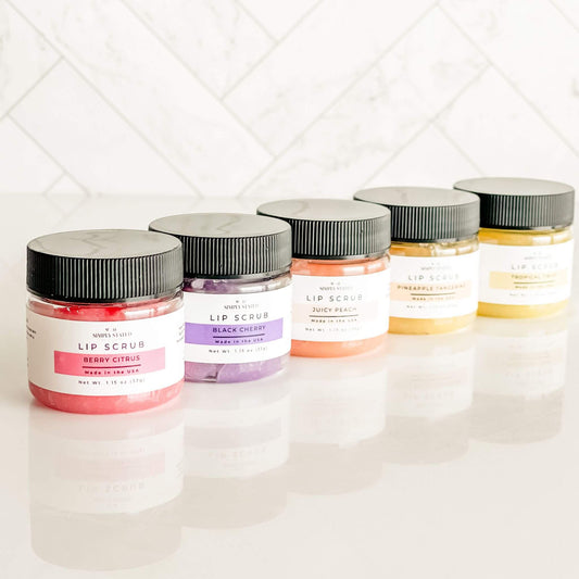 Assorted Simply Stated Bath & Body lip scrubs in a variety of scents, including Berry Citrus, Black Cherry, Juicy Peach, and Pineapple Tangerine, displayed in a lineup with vibrant colors.