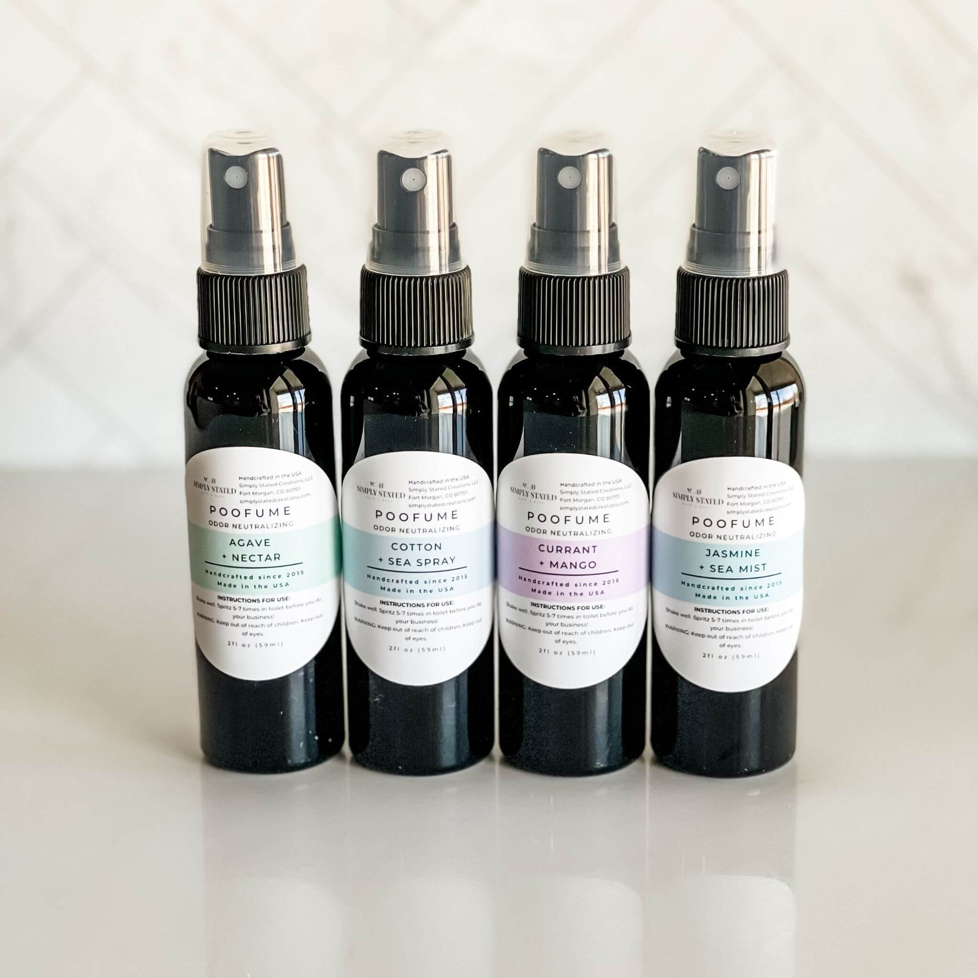 Group of four 2oz Simply Stated Poofume bottles in agave + nectar, cotton + sea spray, currant + mango, and jasmine + sea mist scents.