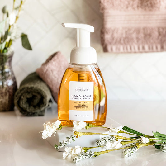 Hand soap bottle with a label on a surface with flowers and towels in the background
