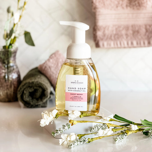 Hand soap bottle with a label on a surface with flowers and towels in the background