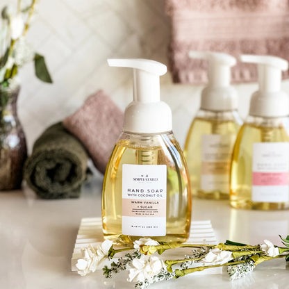 Hand soap bottle with pump dispenser on a decorative stand with flowers and soft background