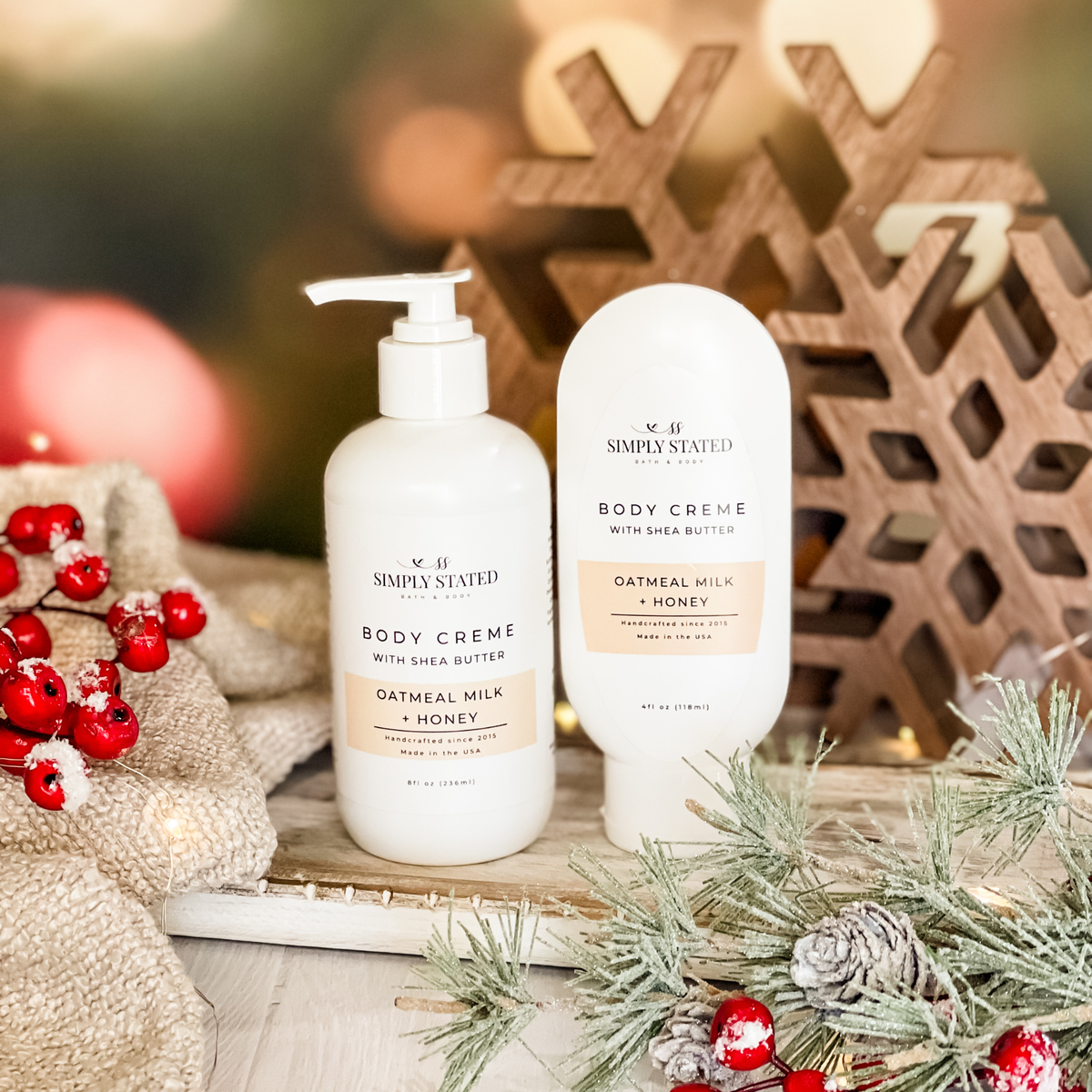 Simply Stated Oatmeal Milk + Honey Body Creme with shea butter, pump and tube sizes, with wooden snowflakes and berries.