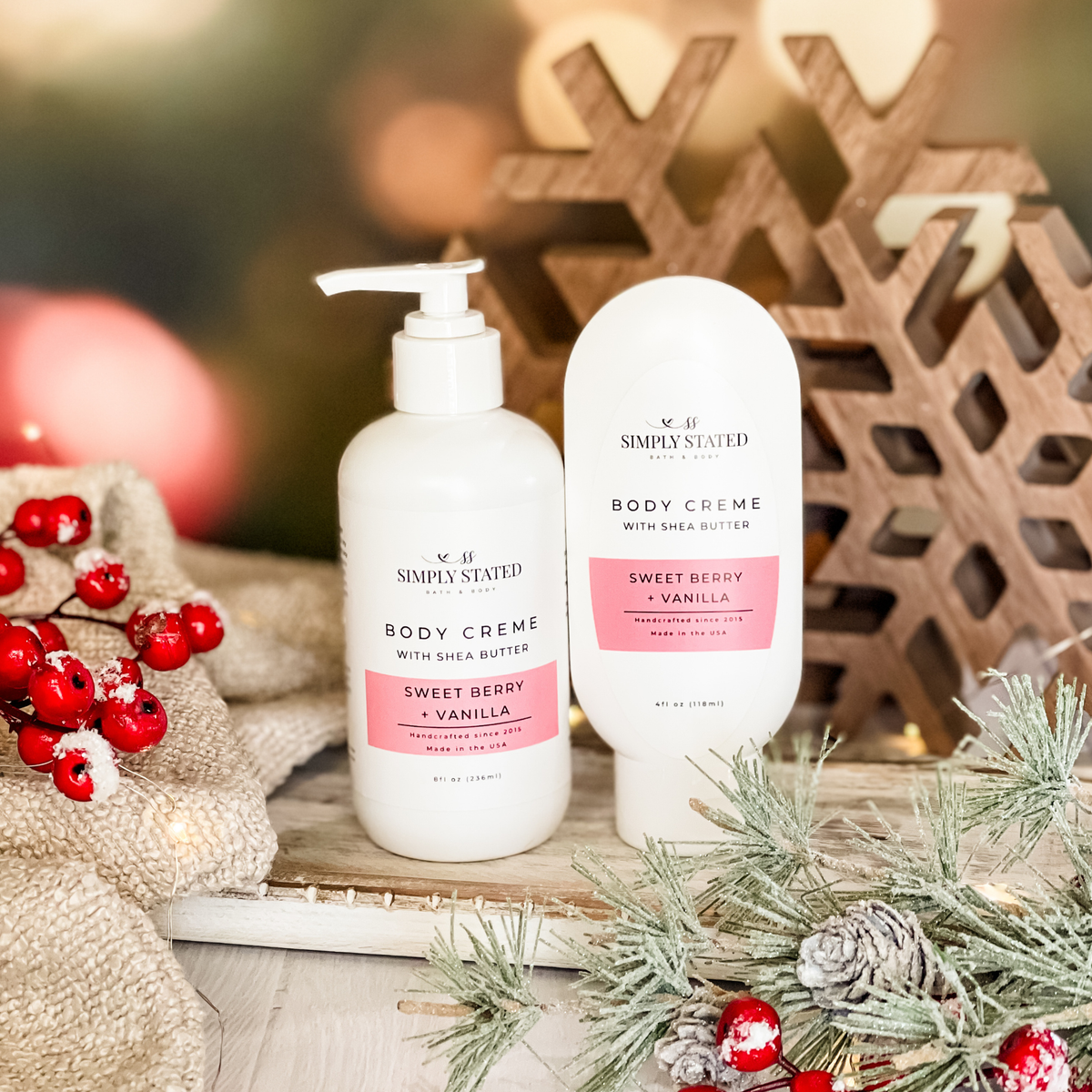 Simply Stated Sweet Berry + Vanilla Body Creme with shea butter, pump and tube sizes, with wooden snowflakes and berries.