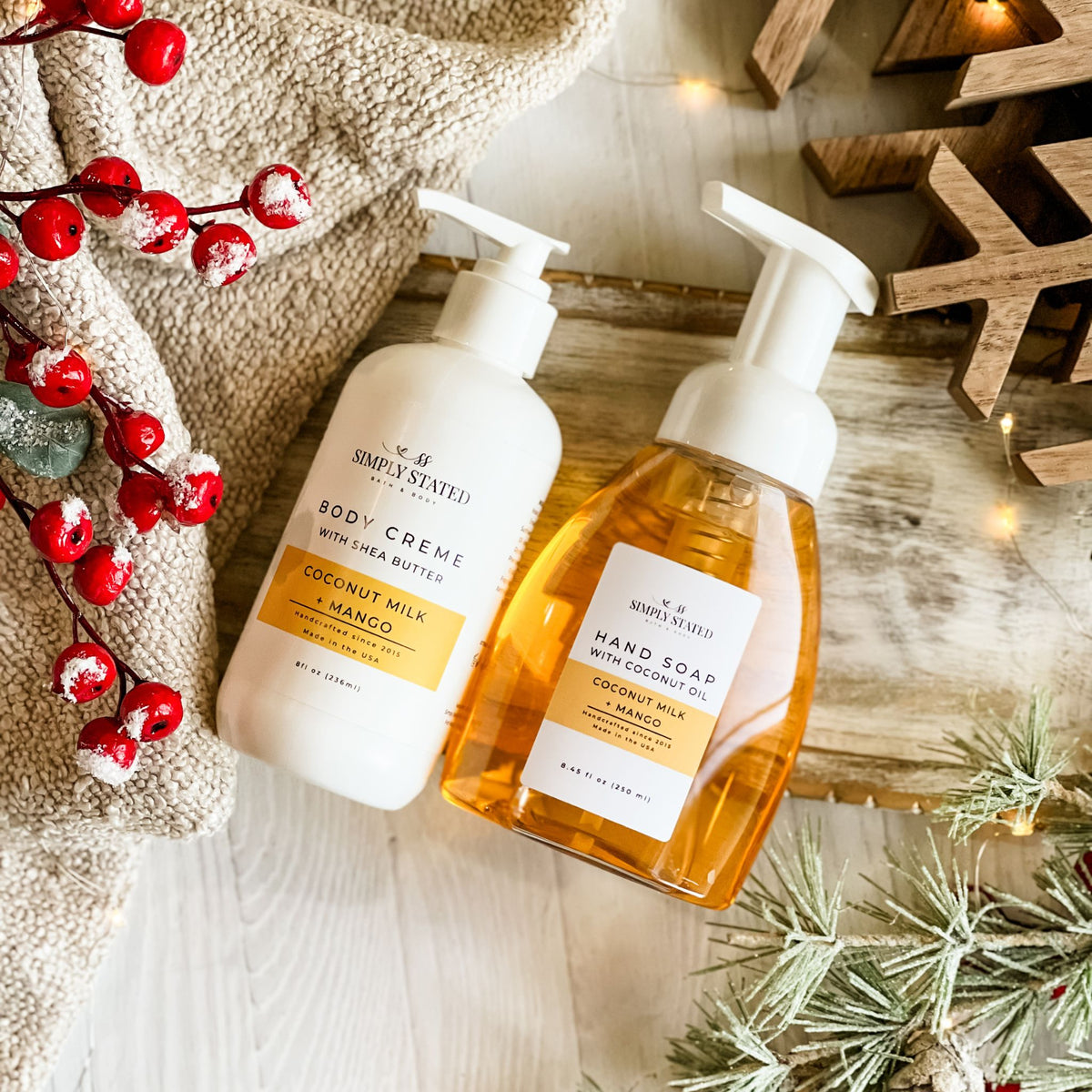 Simply Stated Coconut Milk + Mango Body Creme and Foaming Hand Soap duo, styled with berries and frosted pine.