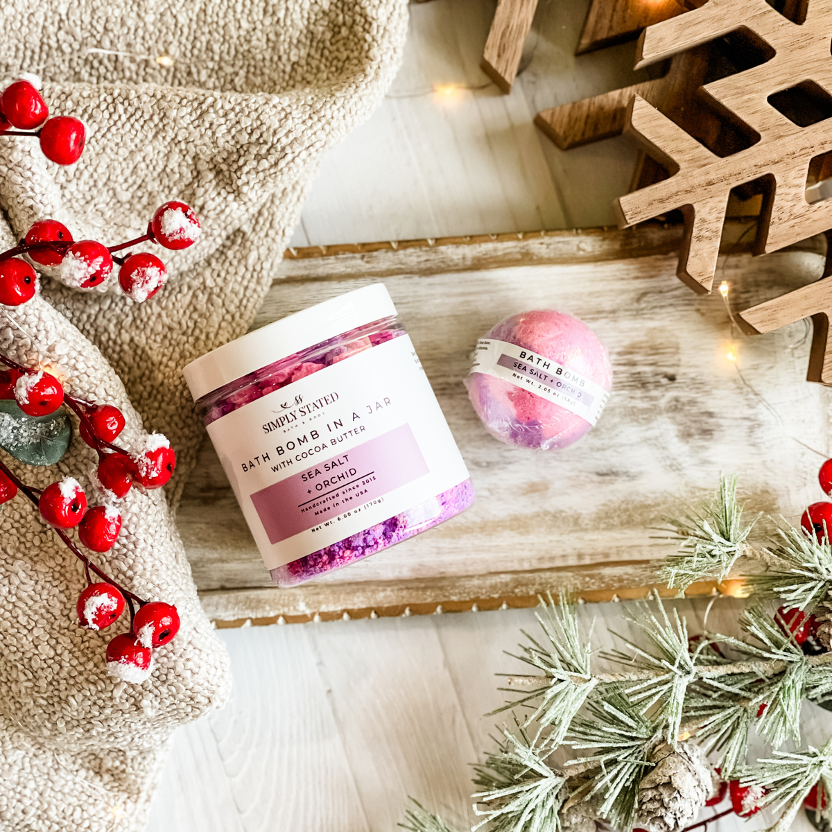 Simply Stated Sea Salt + Orchid Bath Bomb in a Jar with cocoa butter and a single bath bomb, with berries and pine.