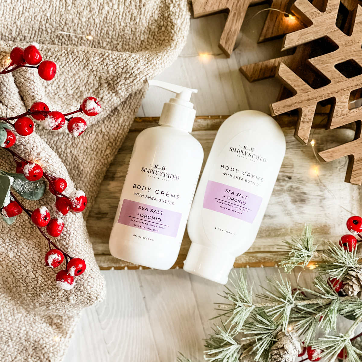 Simply Stated Sea Salt + Orchid Body Creme with shea butter, pump and tube sizes, flat lay with berries and frosted pine.