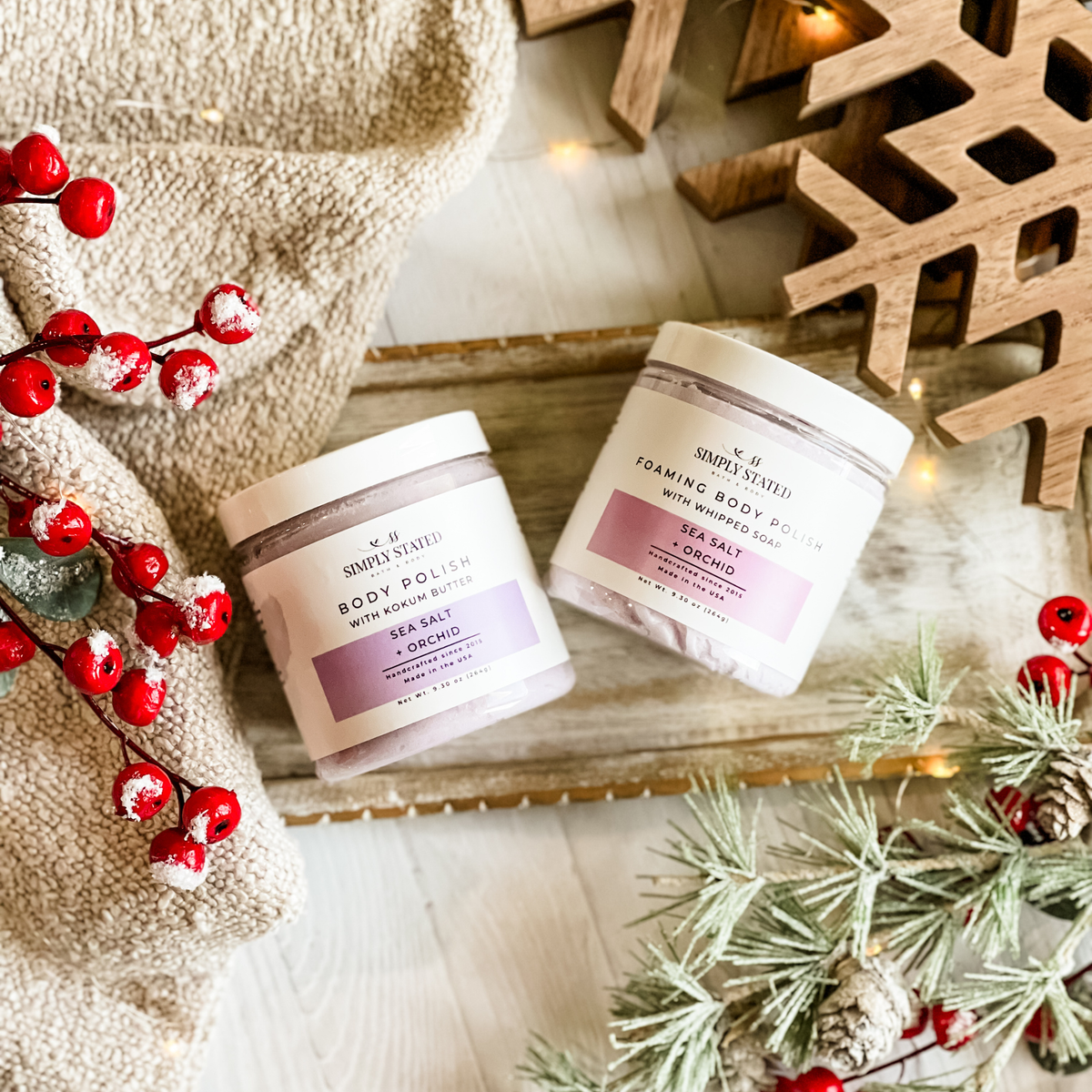 Simply Stated Sea Salt + Orchid Body Polish and Foaming Body Polish duo, with berries, wooden snowflake, and frosted pine.
