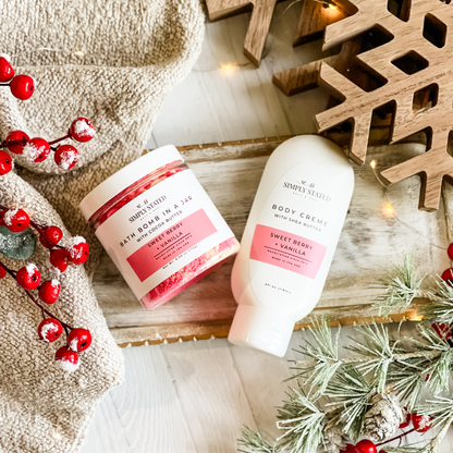 Simply Stated Sweet Berry + Vanilla Bath Bomb in a Jar and Body Creme duo, with wooden snowflake, berries, and frosted pine.