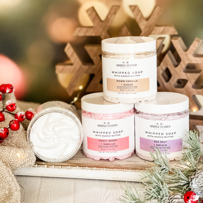 Simply Stated whipped soap with mango butter in three scents, stacked with an open jar beside holiday berries