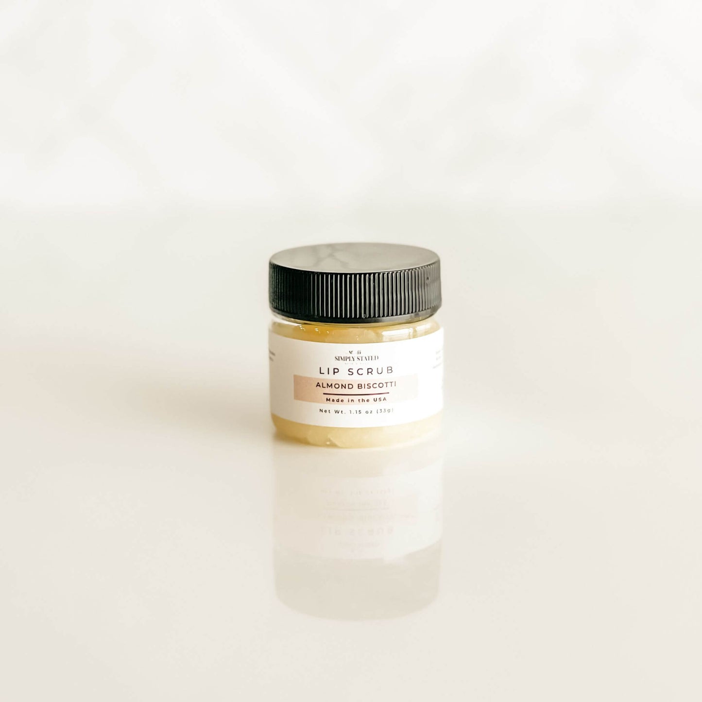 Close-up of a jar of Simply Stated Bath & Body lip scrub in Almond Biscotti, featuring a warm, golden hue and minimalist label design.