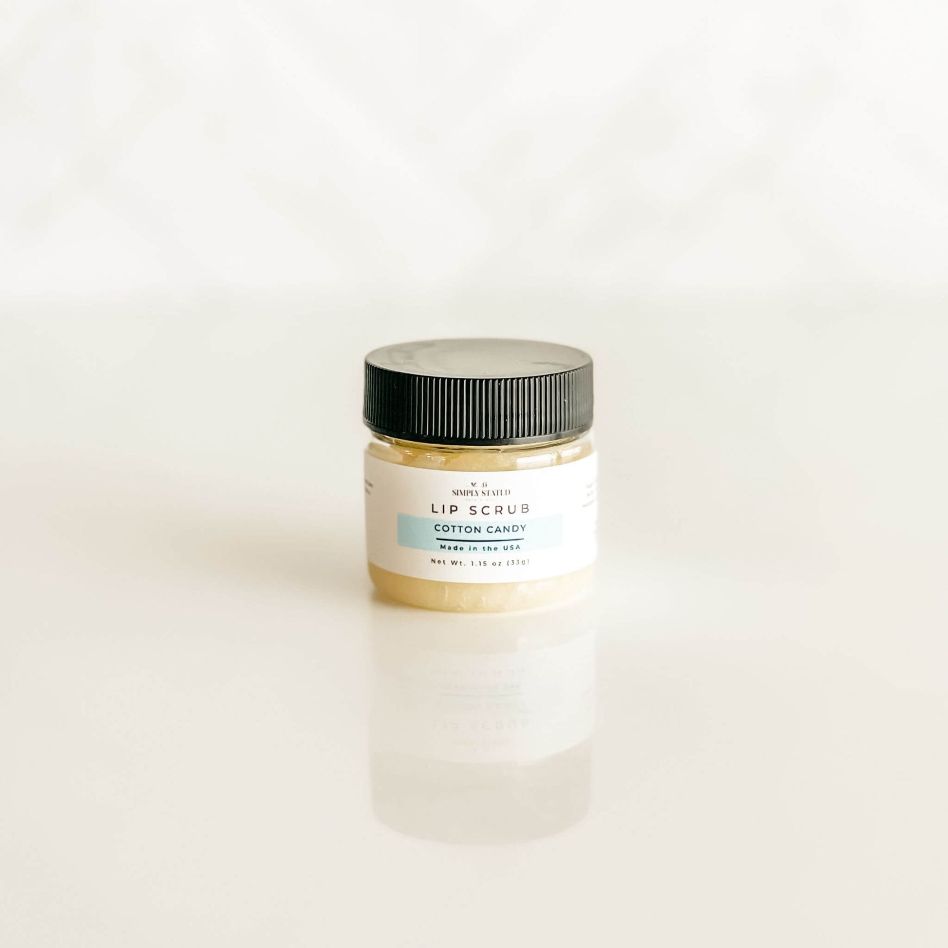 Cotton Candy lip scrub from Simply Stated Bath & Body, featuring a pastel blue label and natural sugar exfoliants for a fun, sweet scent experience.