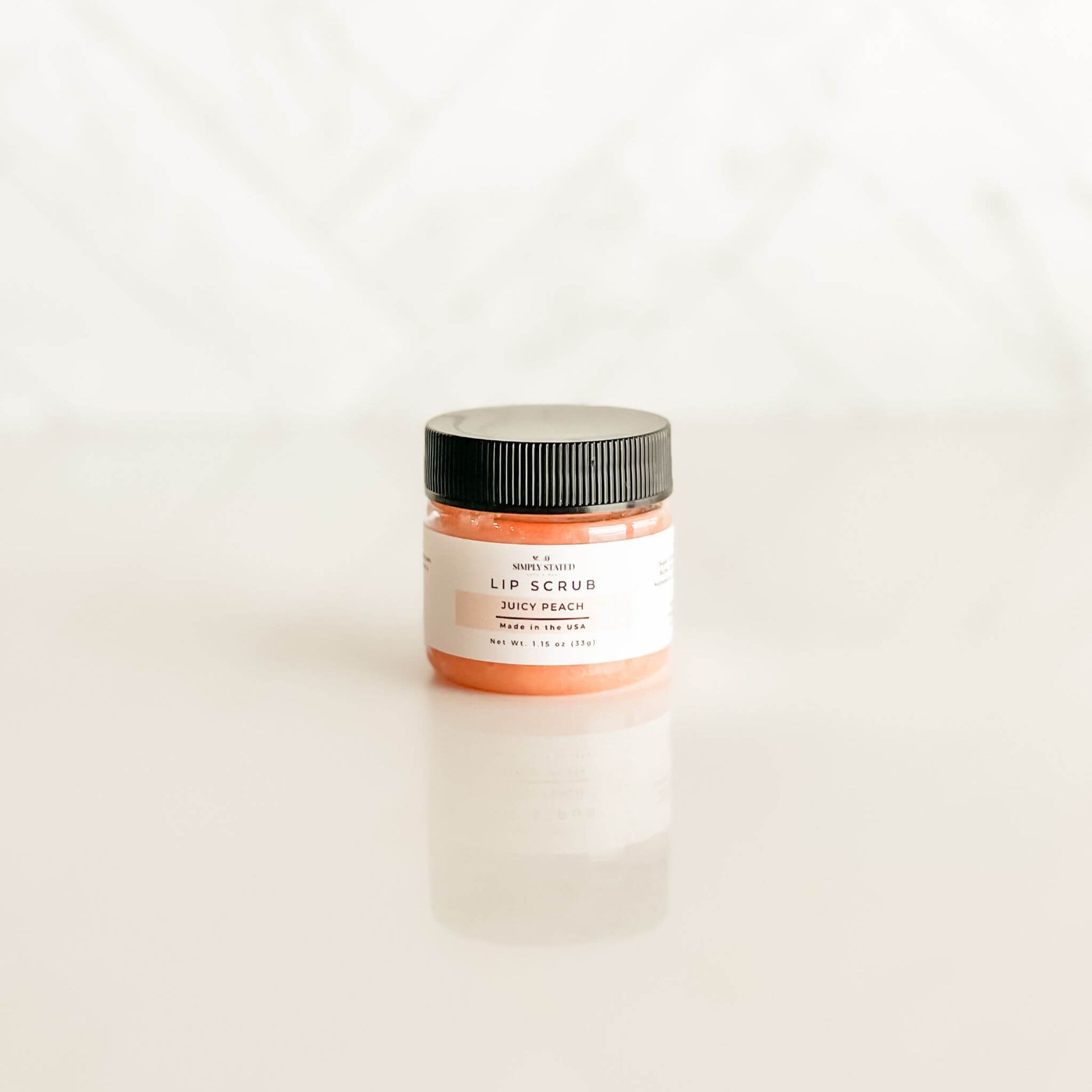 Juicy Peach lip scrub from Simply Stated Bath & Body, with an orange-hued exfoliating formula and a label highlighting its handcrafted quality.