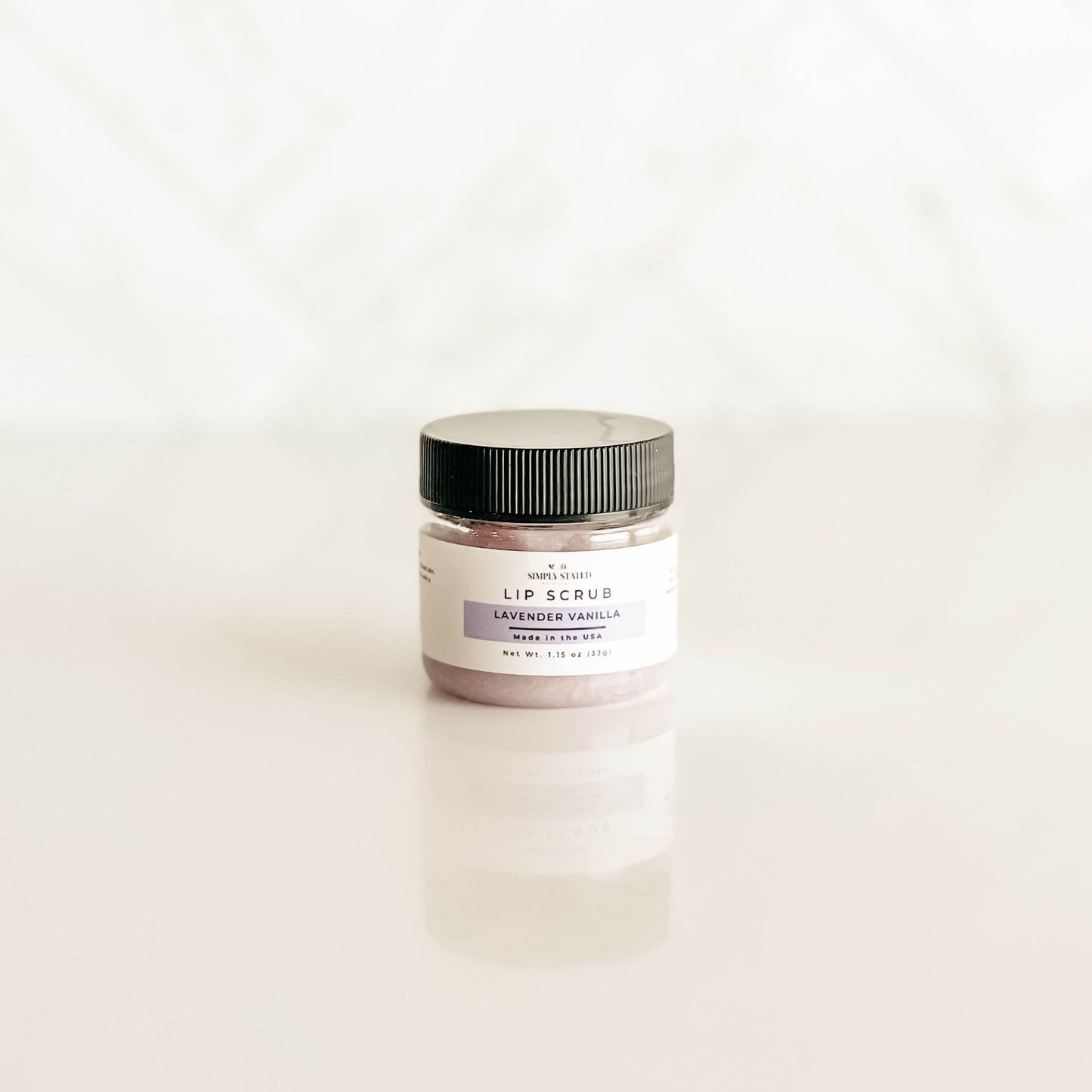 Simply Stated lavender vanilla lip scrub in a clear jar with a light lavender tint, blending floral and vanilla aromas for soothing exfoliation.