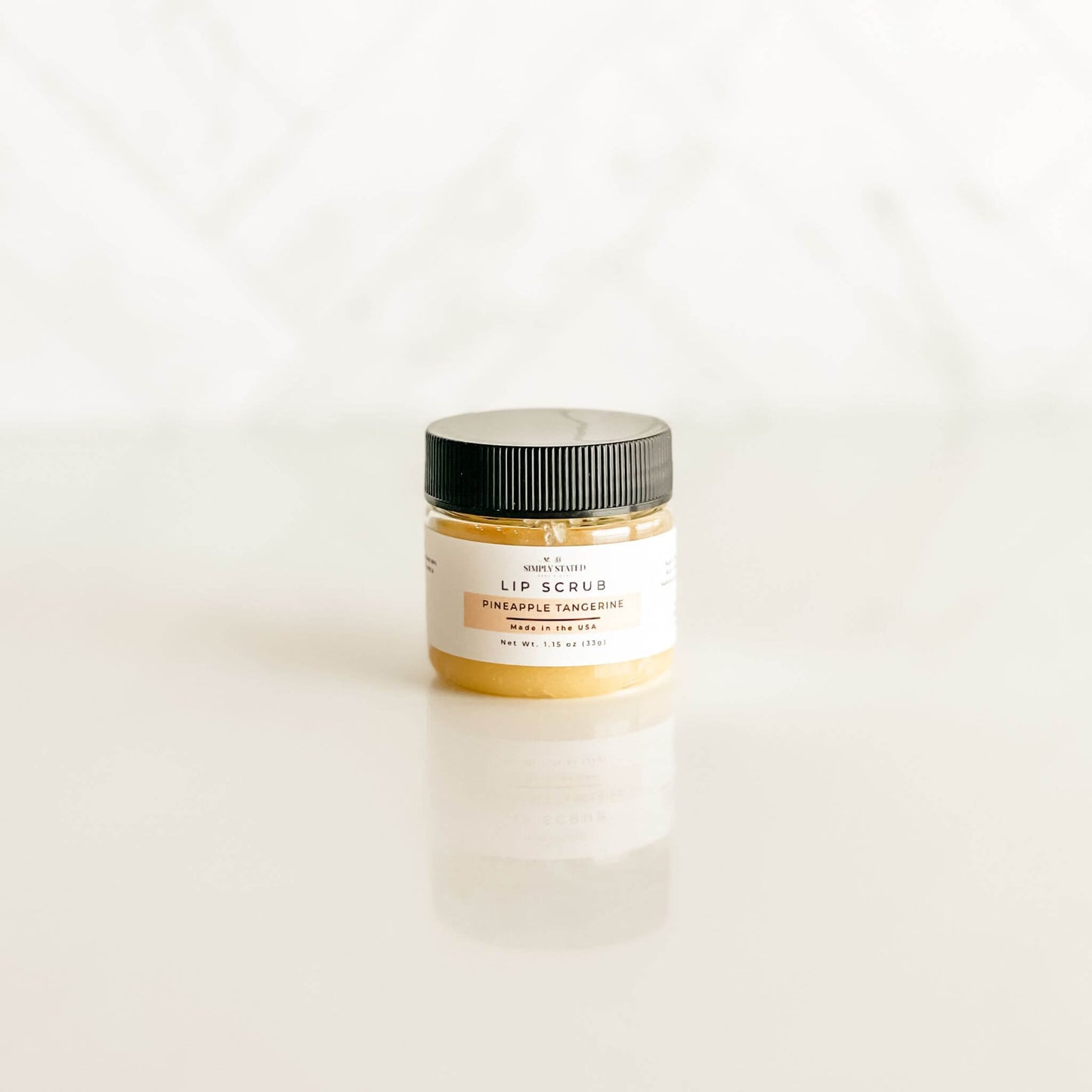 Simply Stated pineapple tangerine lip scrub with a sunny yellow hue, combining tropical citrus scents for a refreshing lip treatment.