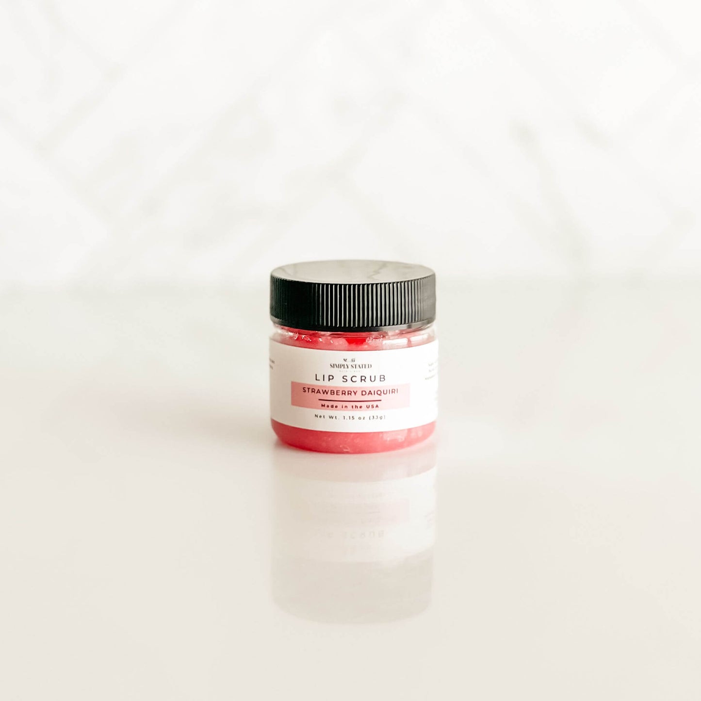 Simply Stated strawberry daiquiri lip scrub with a bold pink-red shade, capturing the sweet and tropical cocktail vibe.