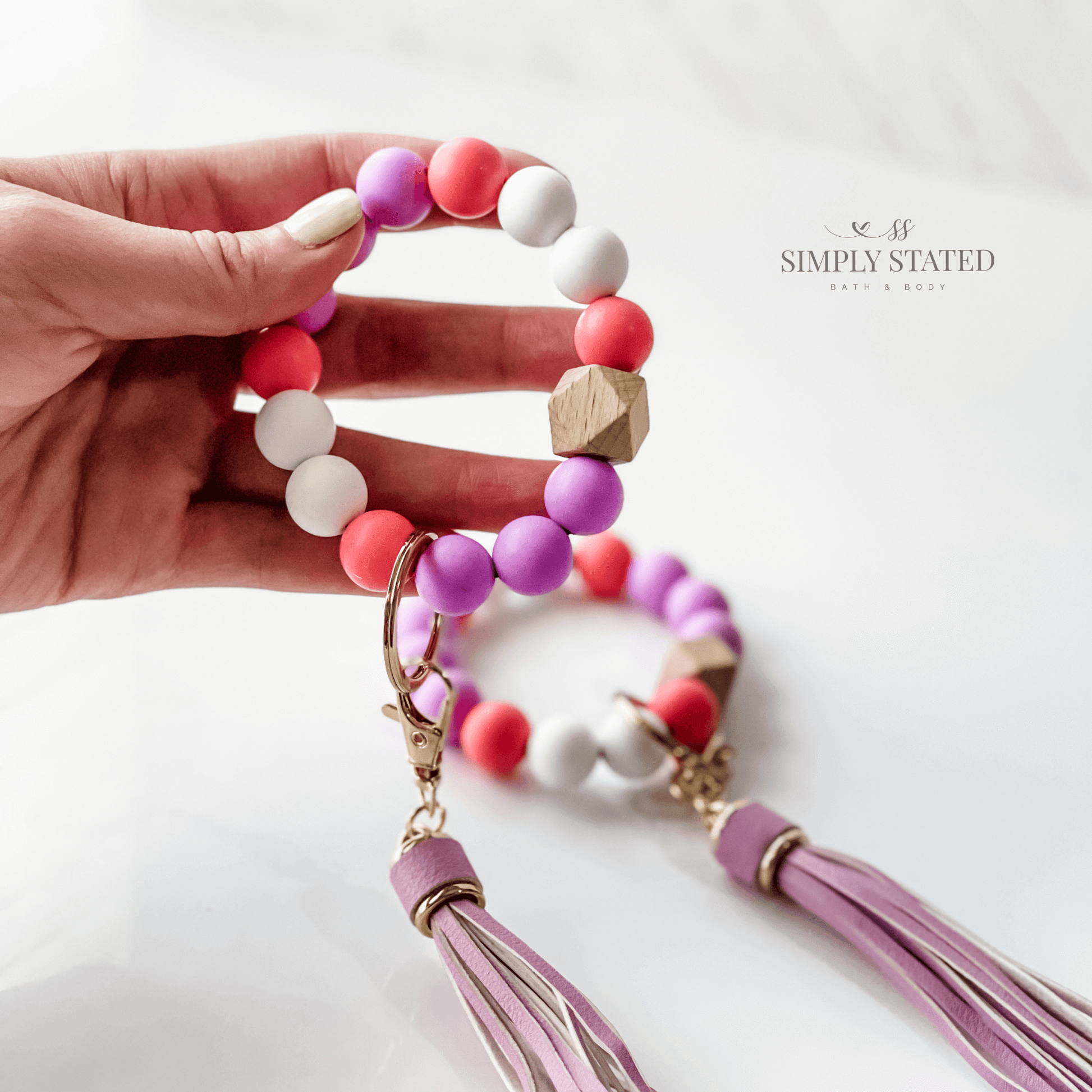 Bangle Keychain made with silicone beads in purple, rose, and white. Tassle included