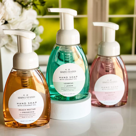 Spring Hand Soap Collection with coconut oil in scents Magnolia + Peony, Peach Nectar + Prosecco, and Verbena + Lemon, displayed in a bright spring-inspired setting.