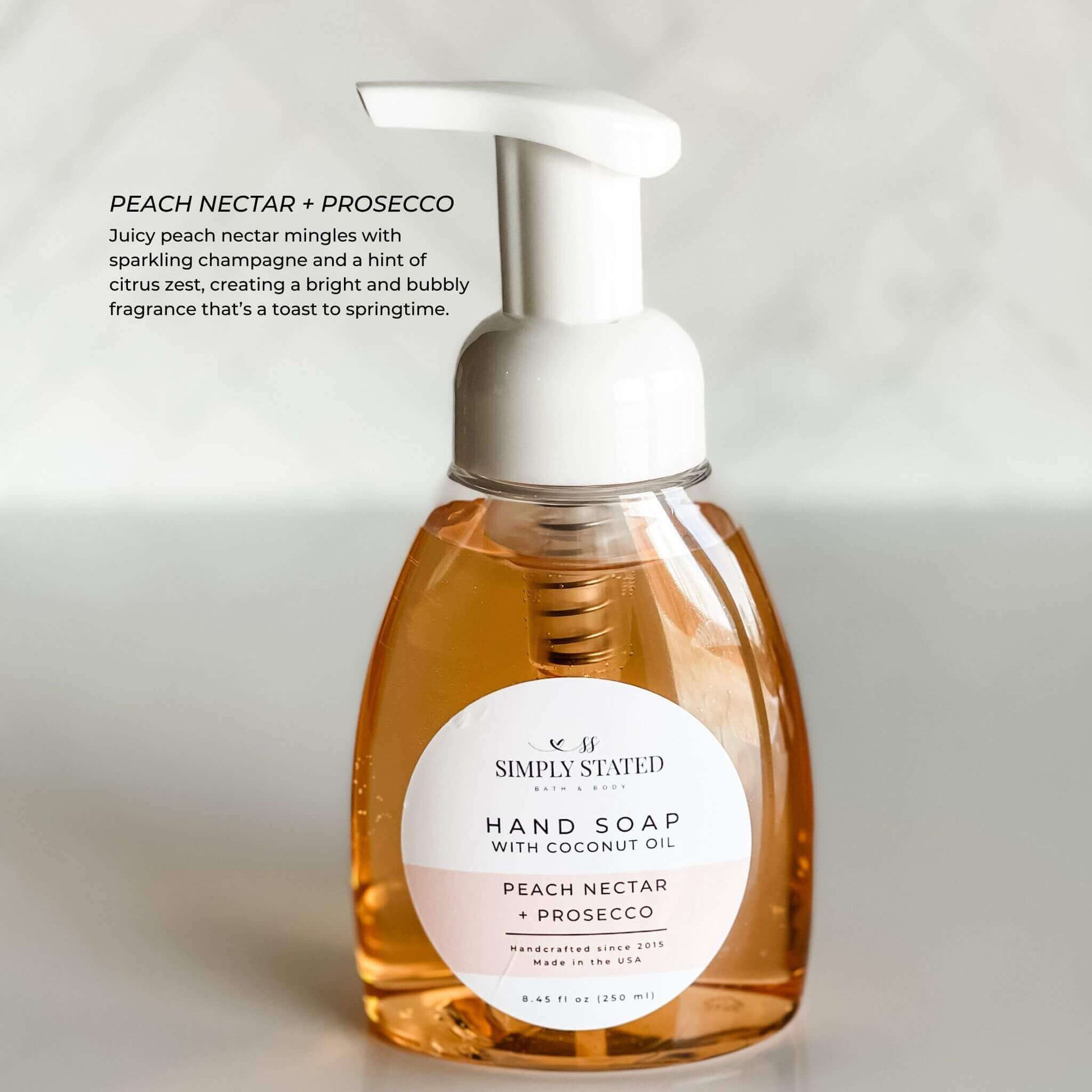 Warm amber-tinted bottle of Peach Nectar + Prosecco Hand Soap, blending juicy peach and sparkling champagne notes.