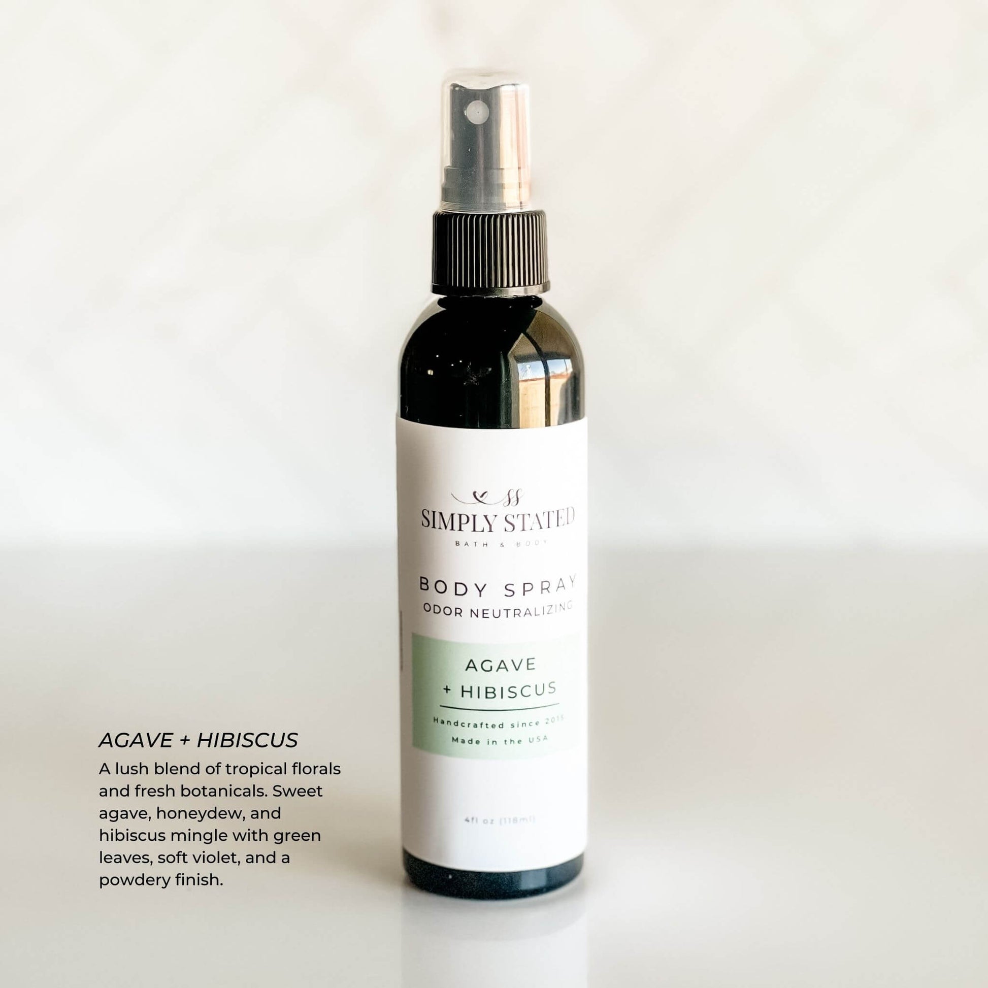 Simply Stated Bath & Body Agave + Hibiscus Body Spray with odor-neutralizing formula in a sleek black 4 oz bottle, featuring a tropical blend of agave, hibiscus, and botanicals.