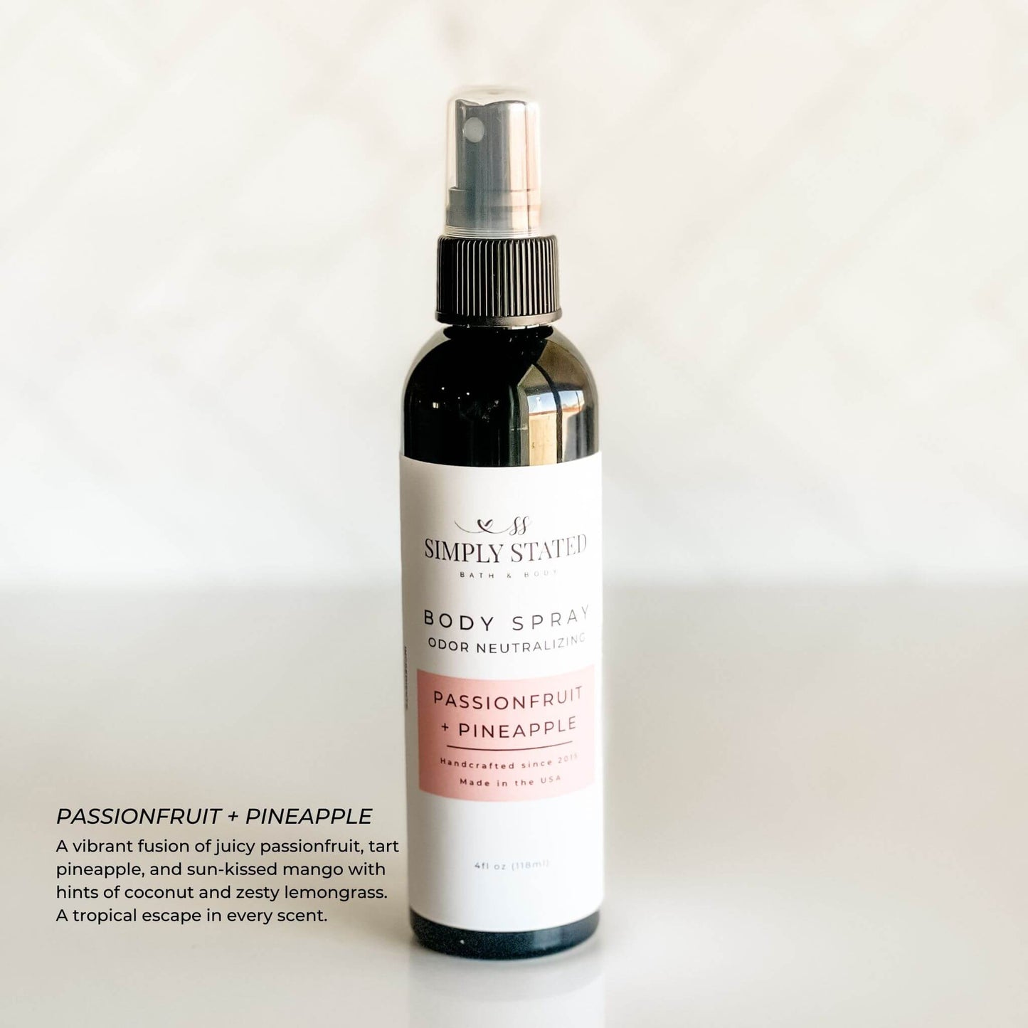 Simply Stated Passionfruit + Pineapple Body Spray in a 4 oz black spray bottle, infused with vibrant tropical notes of mango, pineapple, and coconut.